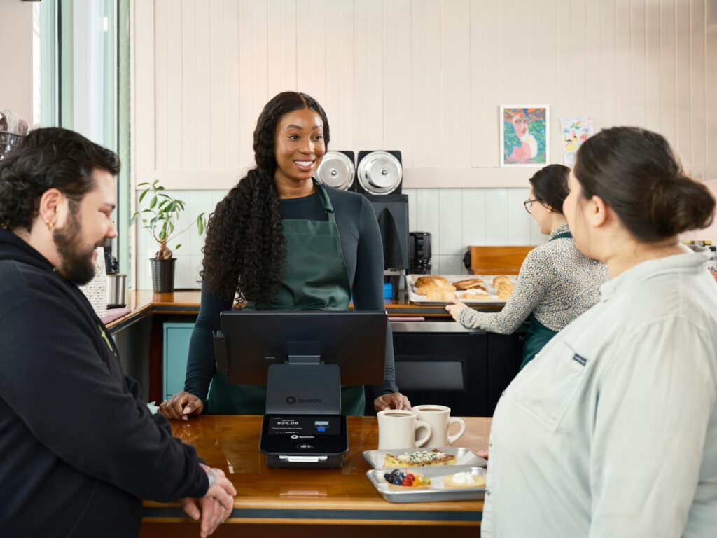 Lächelnde Frau bedient Gäste an einem Café-Tresen