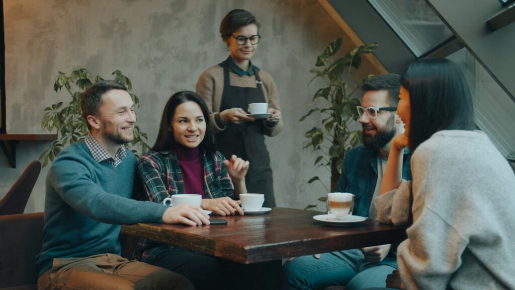Eine Gruppe unterhält sich fröhlich an einem Cafétisch