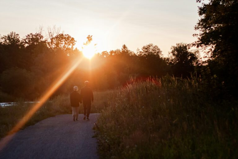 Zwei Personen gehen im Sonnenuntergang einen Weg entlang