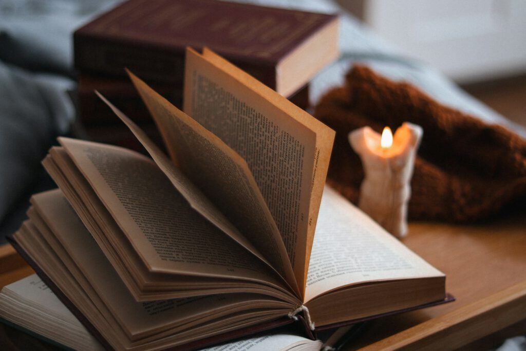 Ein aufgeschlagenes Buch liegt neben einer brennenden Kerze